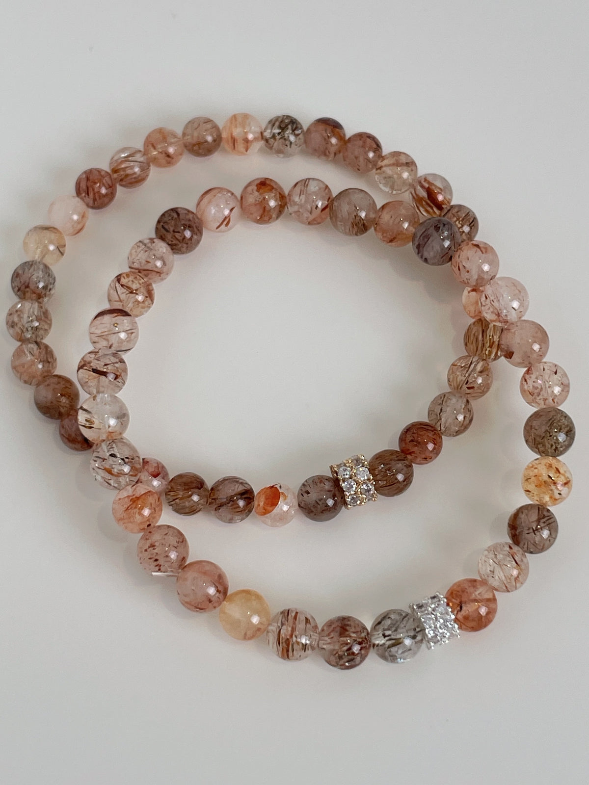 Rutilated quartz bracelet featuring 6mm beads in warm tones, accented with sparkling silver details.