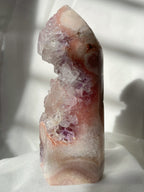 Beautiful purple and pink amethyst tower with sparkling crystal formations, softly illuminated by natural light.