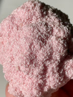 A close-up of a pink rhodochrosite cluster showcasing its textured, sparkling surface.