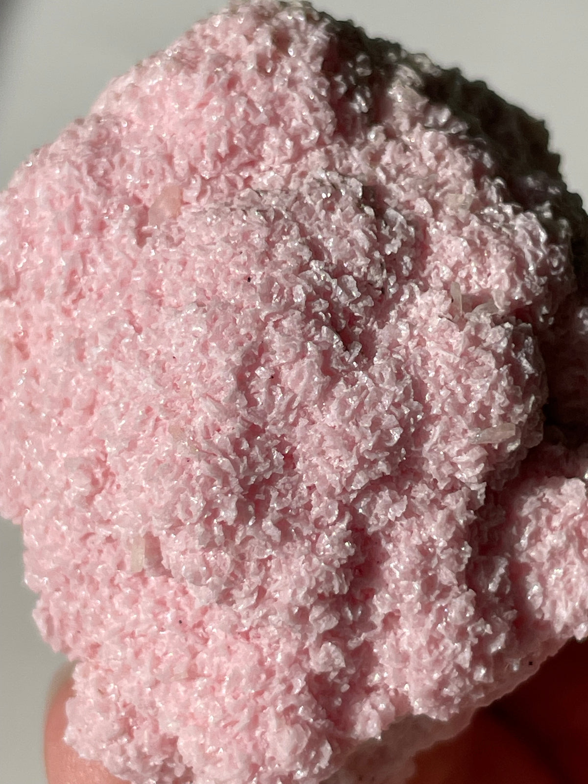 A close-up of a pink rhodochrosite cluster showcasing its textured, sparkling surface.