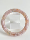 Beautiful flower agate bangle showcasing soft pink hues and natural patterns, displayed beside a clear stand.