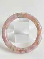 Beautiful flower agate bangle showcasing soft pink hues and natural patterns, displayed beside a clear stand.