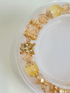 A vibrant yellow fluorite bracelet featuring 9mm beads, accented with golden and peach-colored elements.