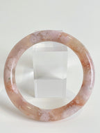 Beautiful flower agate bangle showcasing soft pink hues and unique patterns, displayed on a clear stand.