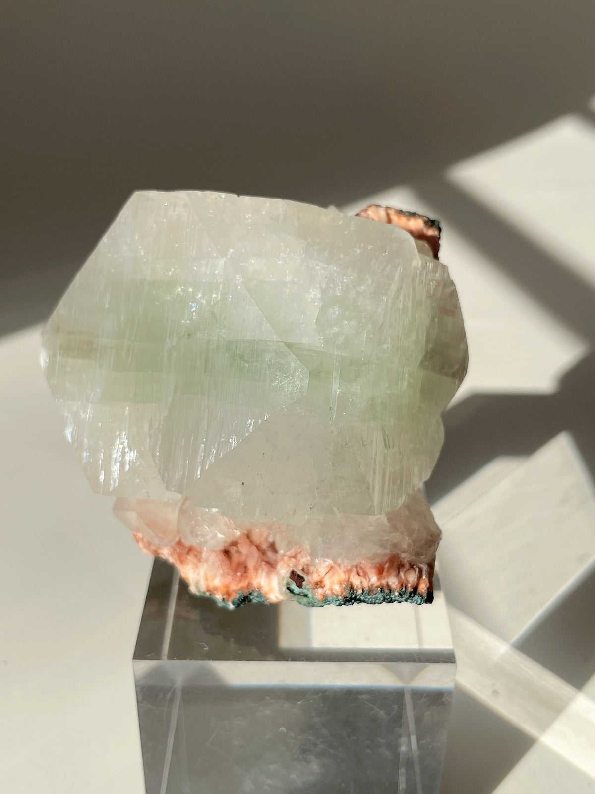 Beautiful crystal specimen featuring pink Heulandite and Apophyllite on a clear display stand, showcasing natural textures.
