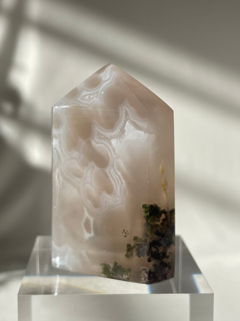 Scenic moss agate crystal tower with unique patterns and earthy tones, elegantly displayed on a clear base.