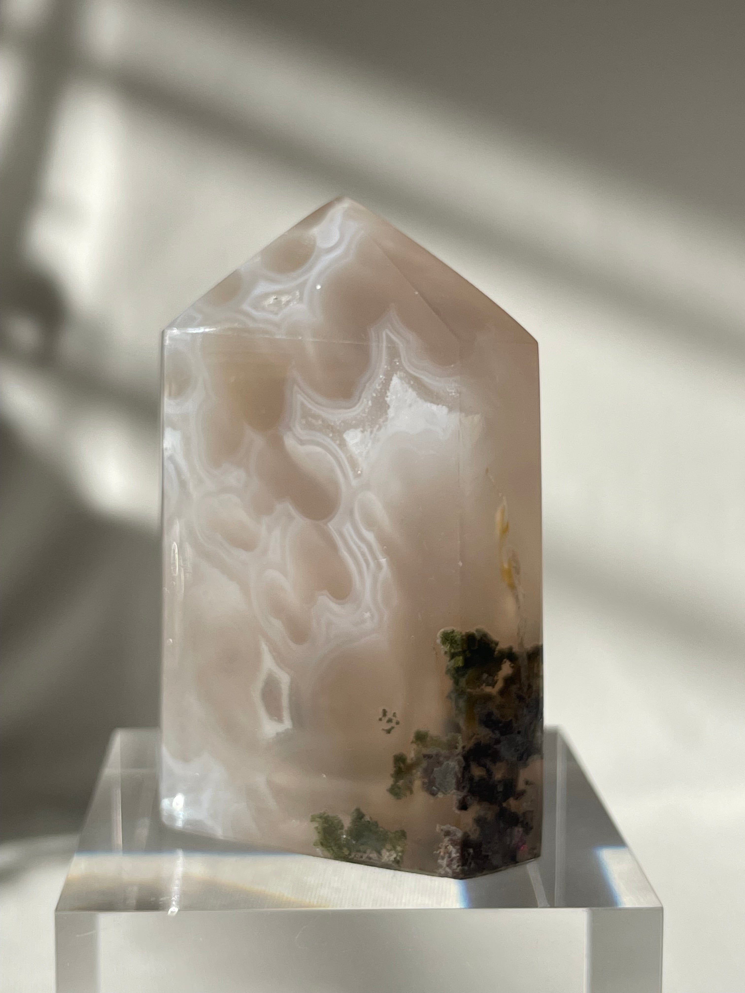 Scenic moss agate crystal tower with unique patterns and earthy tones, elegantly displayed on a clear base.