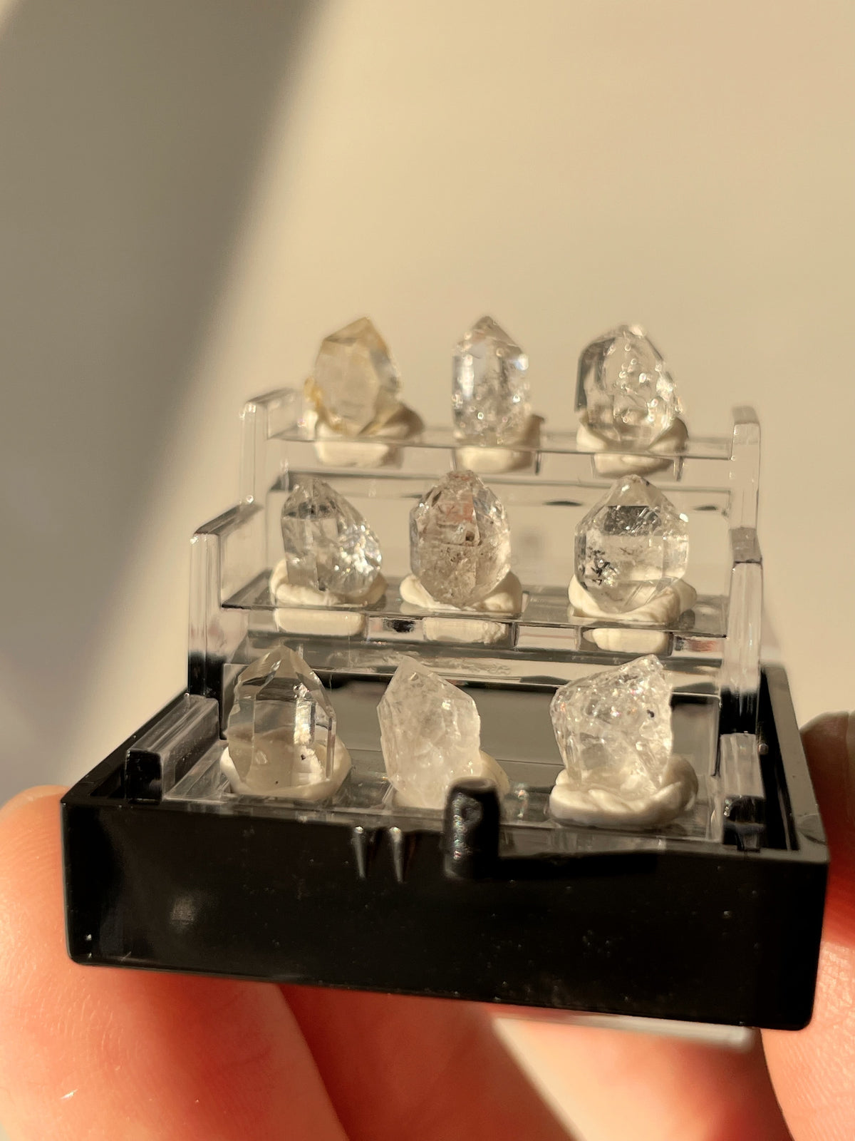 Nine mini Herkimer diamonds displayed in a clear box, showcasing their sparkling clarity and unique shapes.