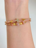 Delicate peach moonstone bracelet featuring gold accents, elegantly worn on a wrist.