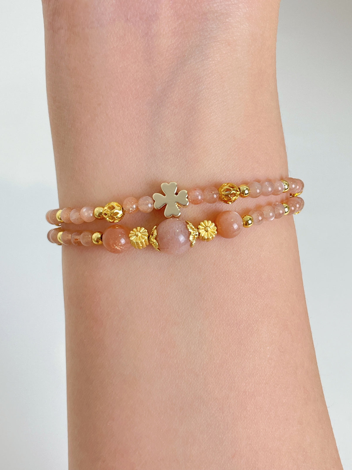Delicate peach moonstone bracelet featuring gold accents, elegantly worn on a wrist.
