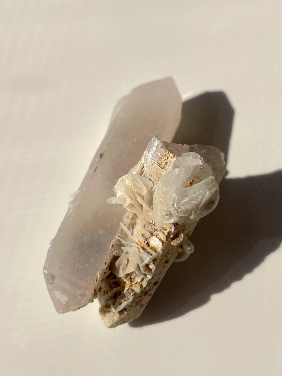 Flower calcite on quartz, showcasing delicate crystal formations with a soft pink hue and intricate textures.