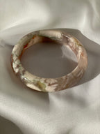 Beautiful flower agate bangle resting on soft fabric, showcasing its unique patterns and colors.