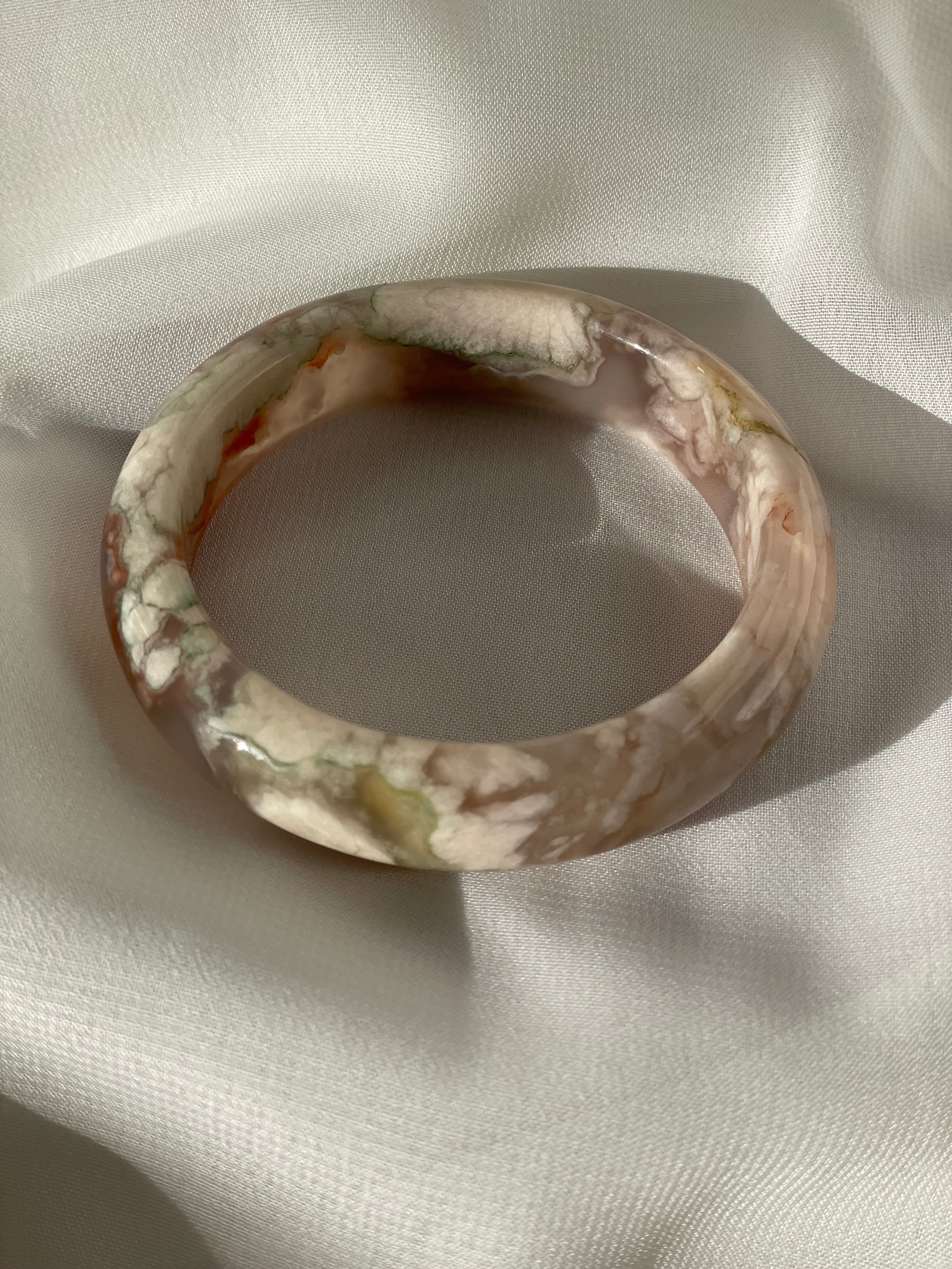 Beautiful flower agate bangle resting on soft fabric, showcasing its unique patterns and colors.