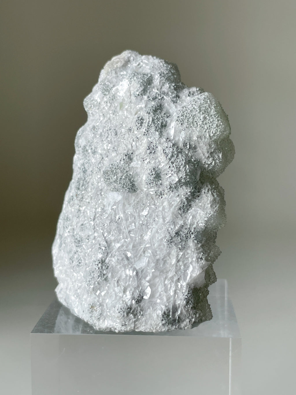 Fujian sugar fluorite specimen with muscovite, showcasing a textured, translucent surface on a clear display stand.