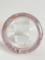 Flower agate bangle featuring soft pink hues and natural patterns, displayed beside a clear acrylic stand.