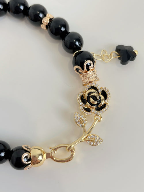 Elegant black obsidian bracelet featuring 8mm beads, adorned with gold accents and a sparkling rose charm.