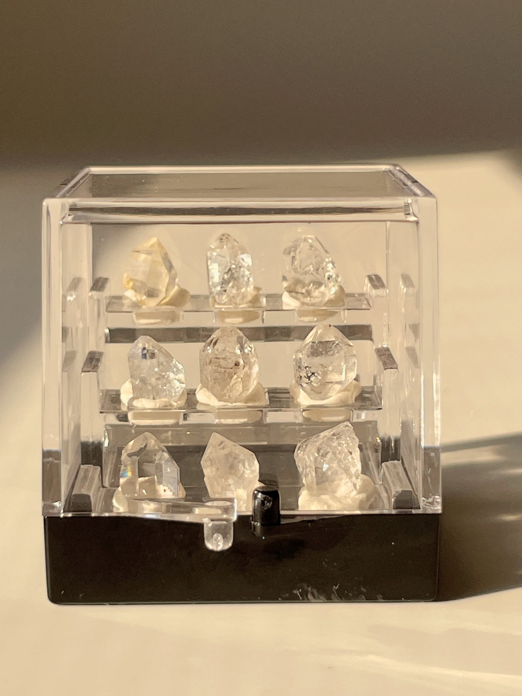 Nine mini Herkimer diamonds displayed in a clear box, showcasing their sparkling clarity and unique shapes.