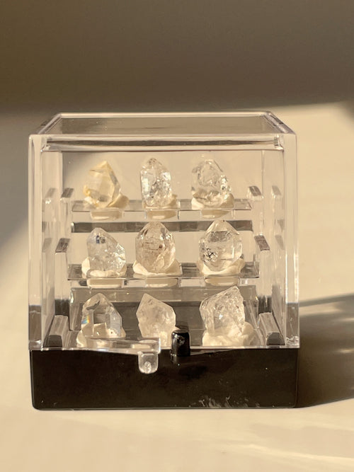 Nine mini Herkimer diamonds displayed in a clear box, showcasing their sparkling clarity and unique shapes.