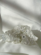 A sparkling apophyllite cluster with clear, crystalline formations resting on a soft white fabric.