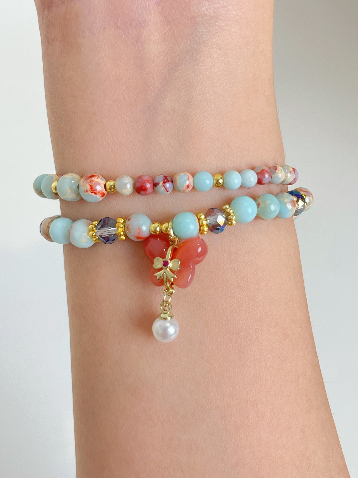 Colorful double bracelet featuring various beads, including turquoise and coral, with a floral charm and pearl accent.