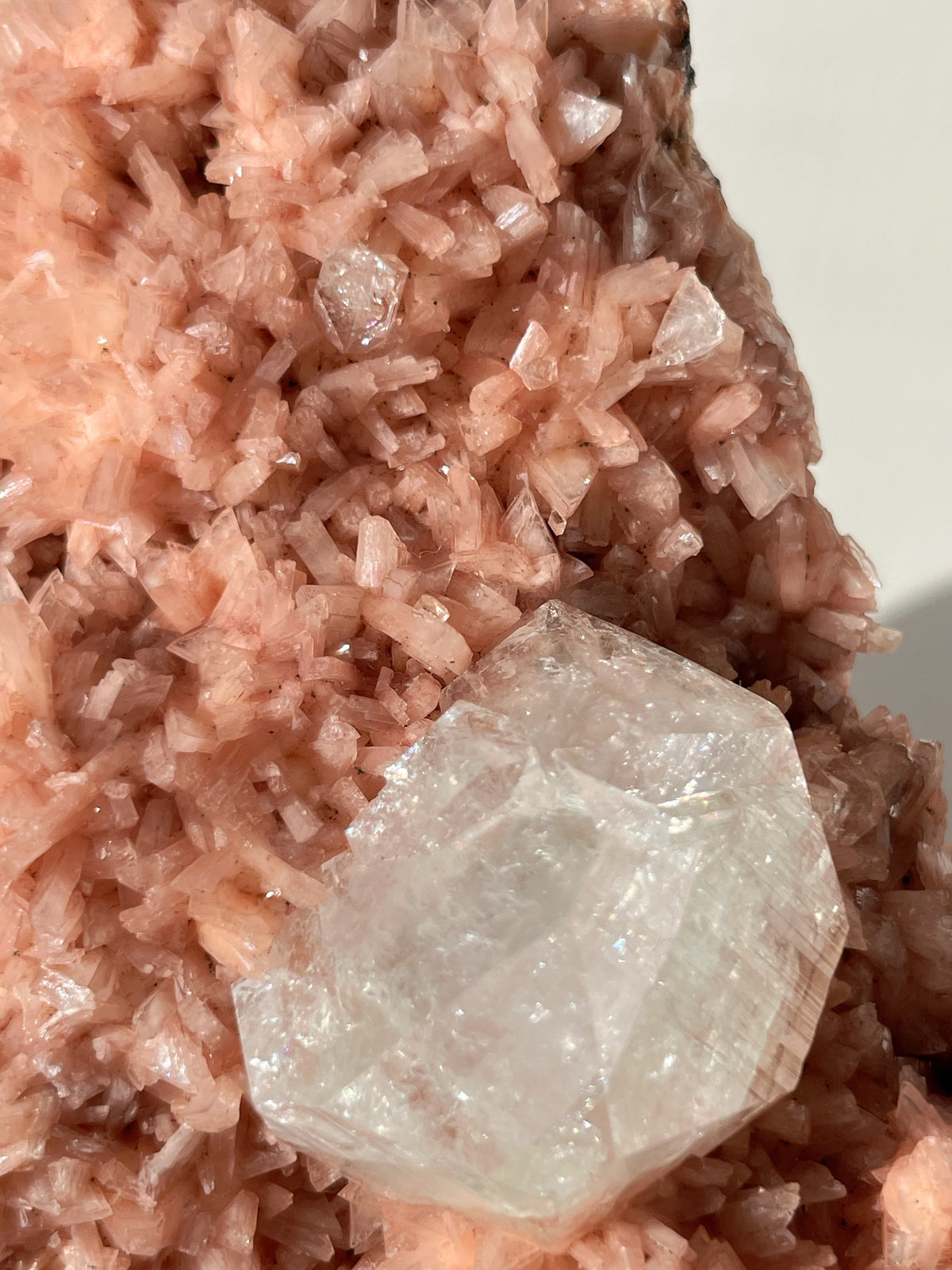 Beautiful pink Heulandite crystal specimen with a clear Apophyllite atop a textured pink mineral base.