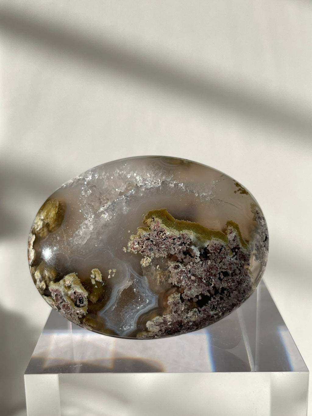 Scenic moss agate palm stone with earthy tones and intricate patterns, displayed on a clear stand.