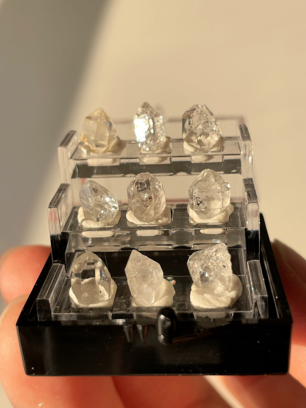 Nine mini Herkimer diamond crystal specimens displayed in a clear box, showcasing their natural beauty and clarity.