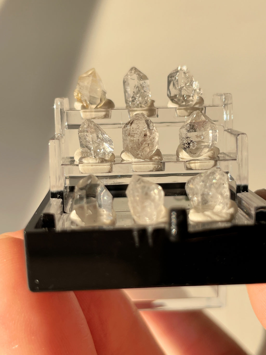 Nine mini Herkimer diamonds displayed in a clear box, showcasing their unique crystal formations.