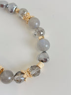 Elegant bracelet featuring grey labradorite beads, sparkling accents, and gold floral details.