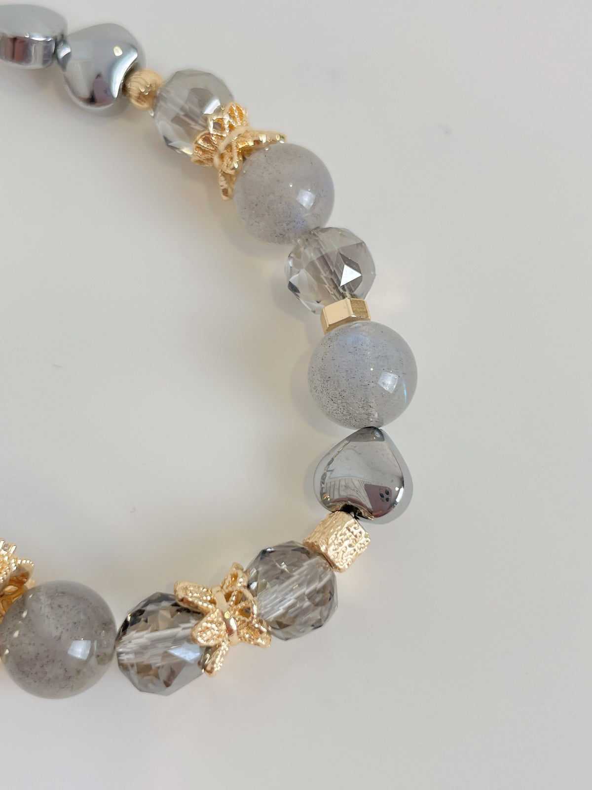 Elegant bracelet featuring grey labradorite beads, sparkling accents, and gold floral details.