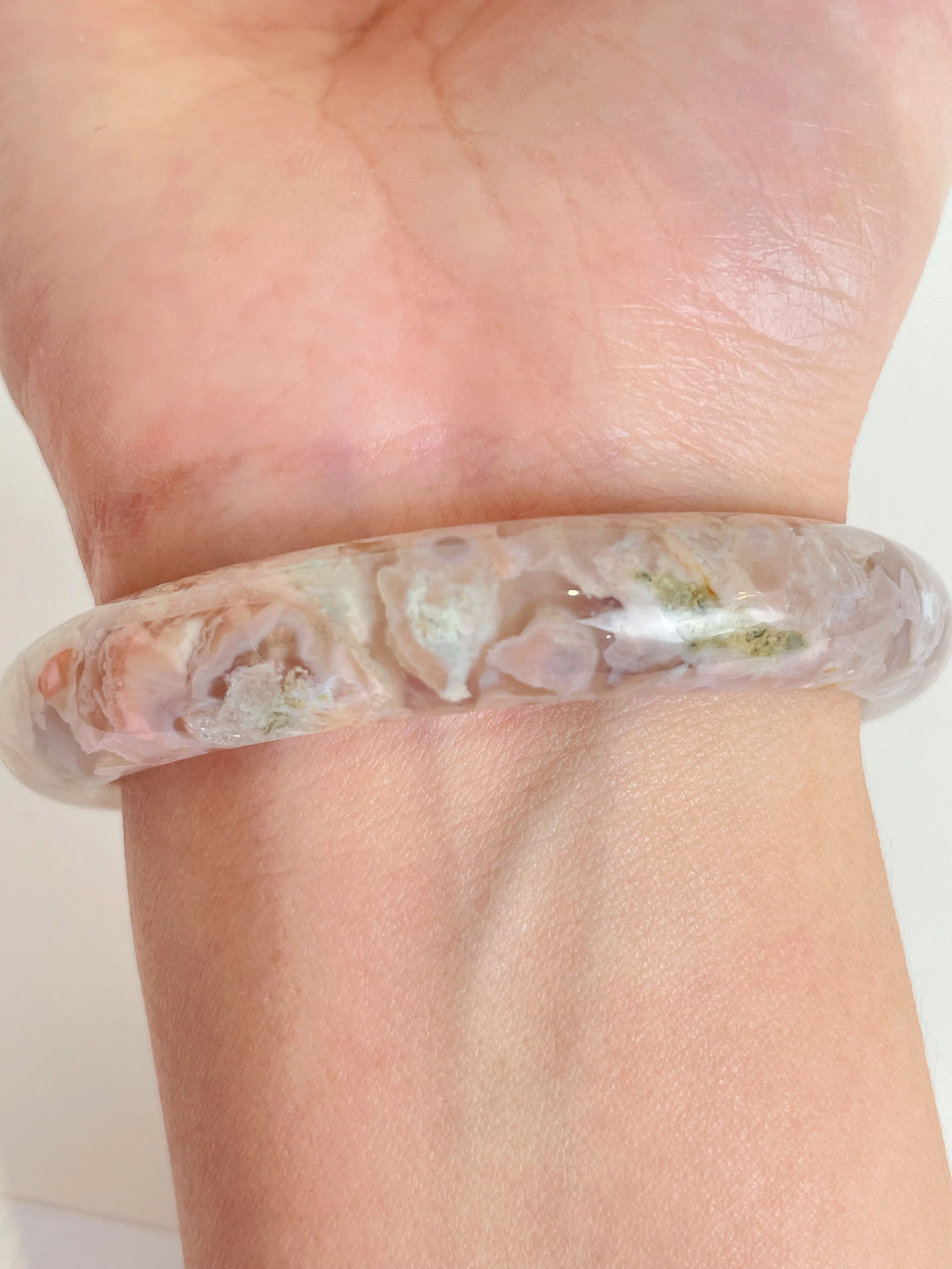 Beautiful flower agate bangle featuring soft pink and green hues, worn on a wrist.