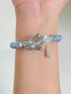 Beautiful Angelite butterfly bracelet featuring 10mm beads and silver floral accents, elegantly worn on a wrist.