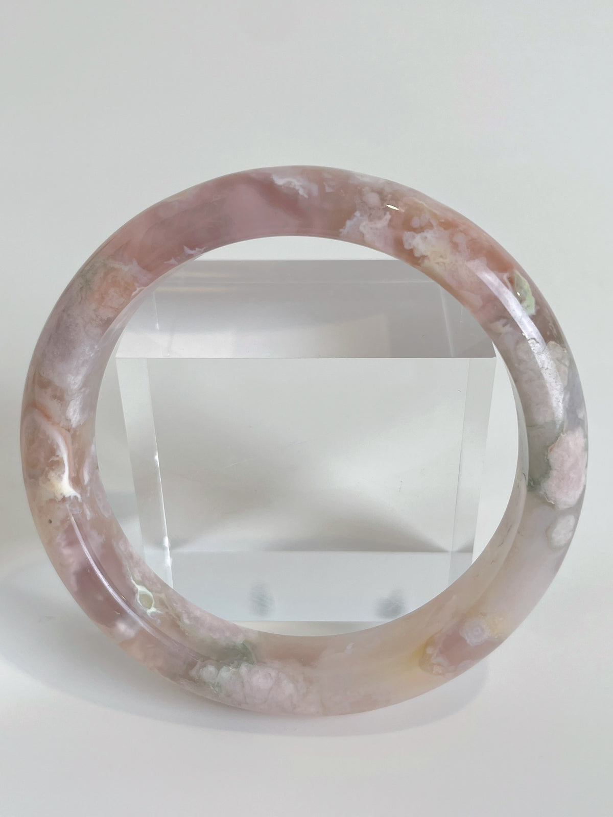 Beautiful flower agate bangle showcasing soft pink hues and floral patterns, displayed against a clear background.