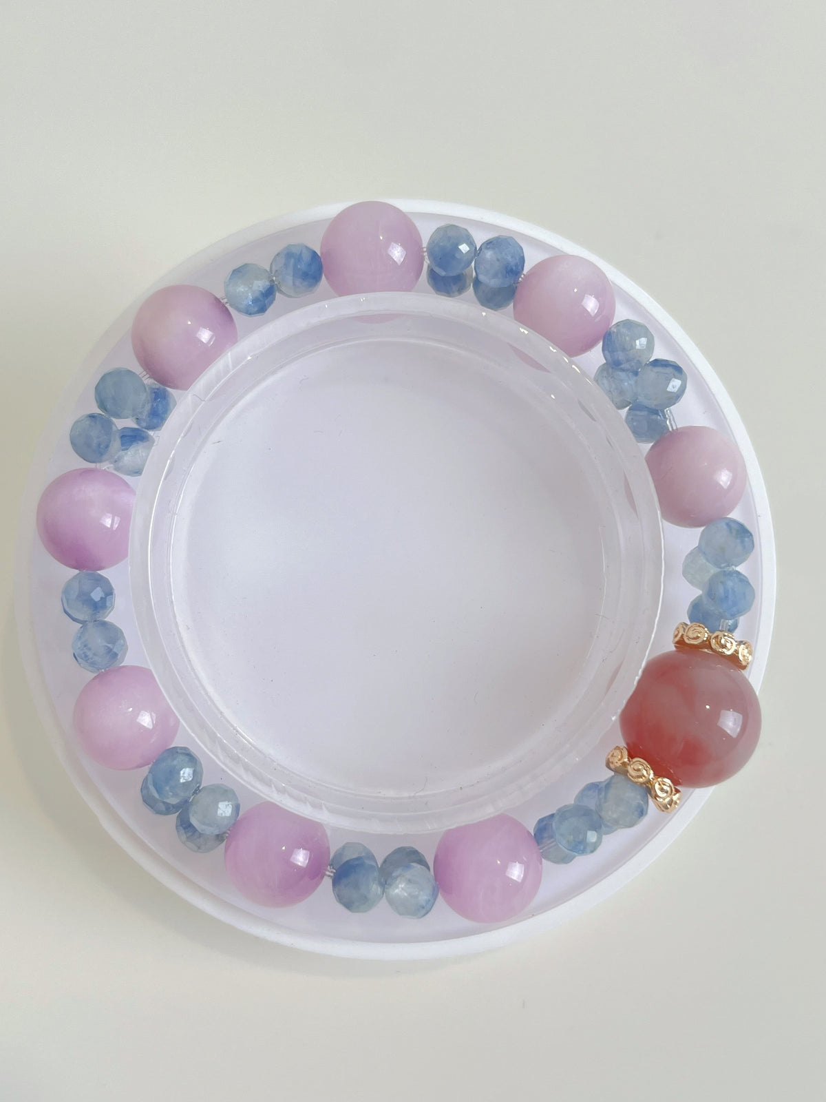 Kunzite and kyanite bracelet featuring 10mm pink and blue crystal beads, elegantly arranged on a display.