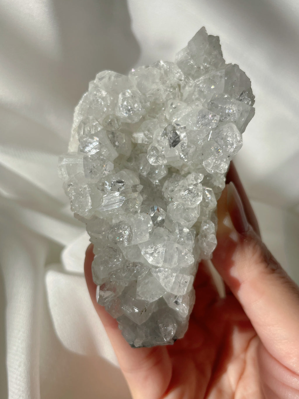 A stunning apophyllite cluster with sparkling crystals, showcasing a natural, textured surface.
