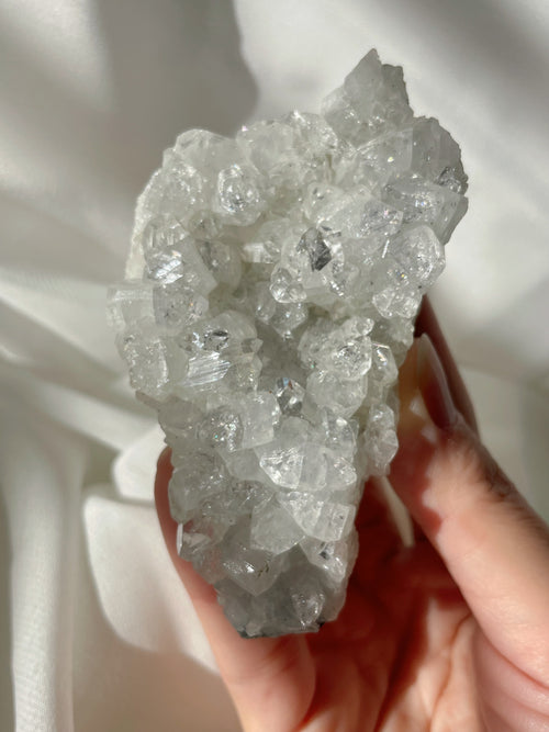 A stunning apophyllite cluster with sparkling crystals, showcasing a natural, textured surface.