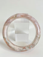 Beautiful flower agate bangle showcasing soft pink hues with natural patterns, displayed on a clear stand.
