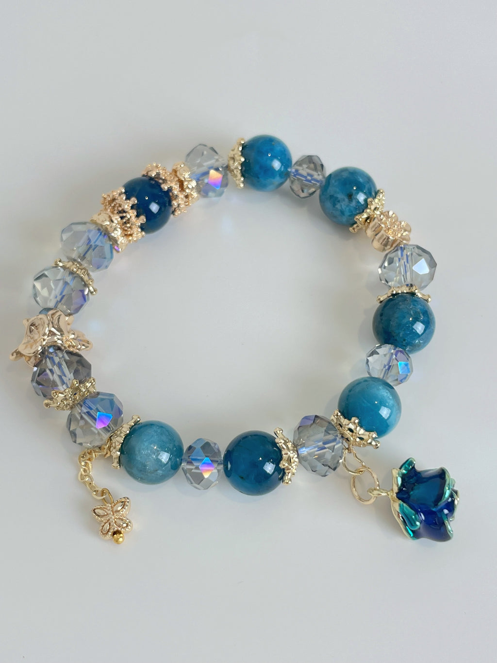 Beautiful blue apatite bracelet featuring 10mm beads, sparkling accents, and charming floral details.
