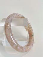 Beautiful flower agate bangle with soft pink hues, displayed on a clear acrylic stand.