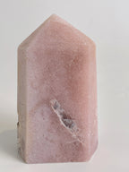 Beautiful pink amethyst tower with a smooth surface and a pointed top, showcasing natural mineral patterns.