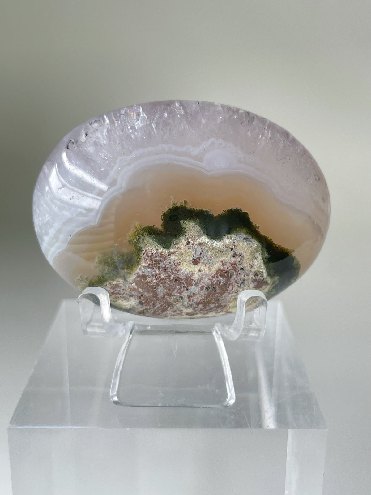 Scenic moss agate palm stone with earthy tones and intricate patterns, displayed on a clear stand.