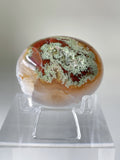 Scenic moss agate palm stone with earthy tones and intricate patterns, displayed on a clear stand.