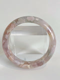 Beautiful flower agate bangle showcasing soft pink and green hues, displayed on a clear stand.