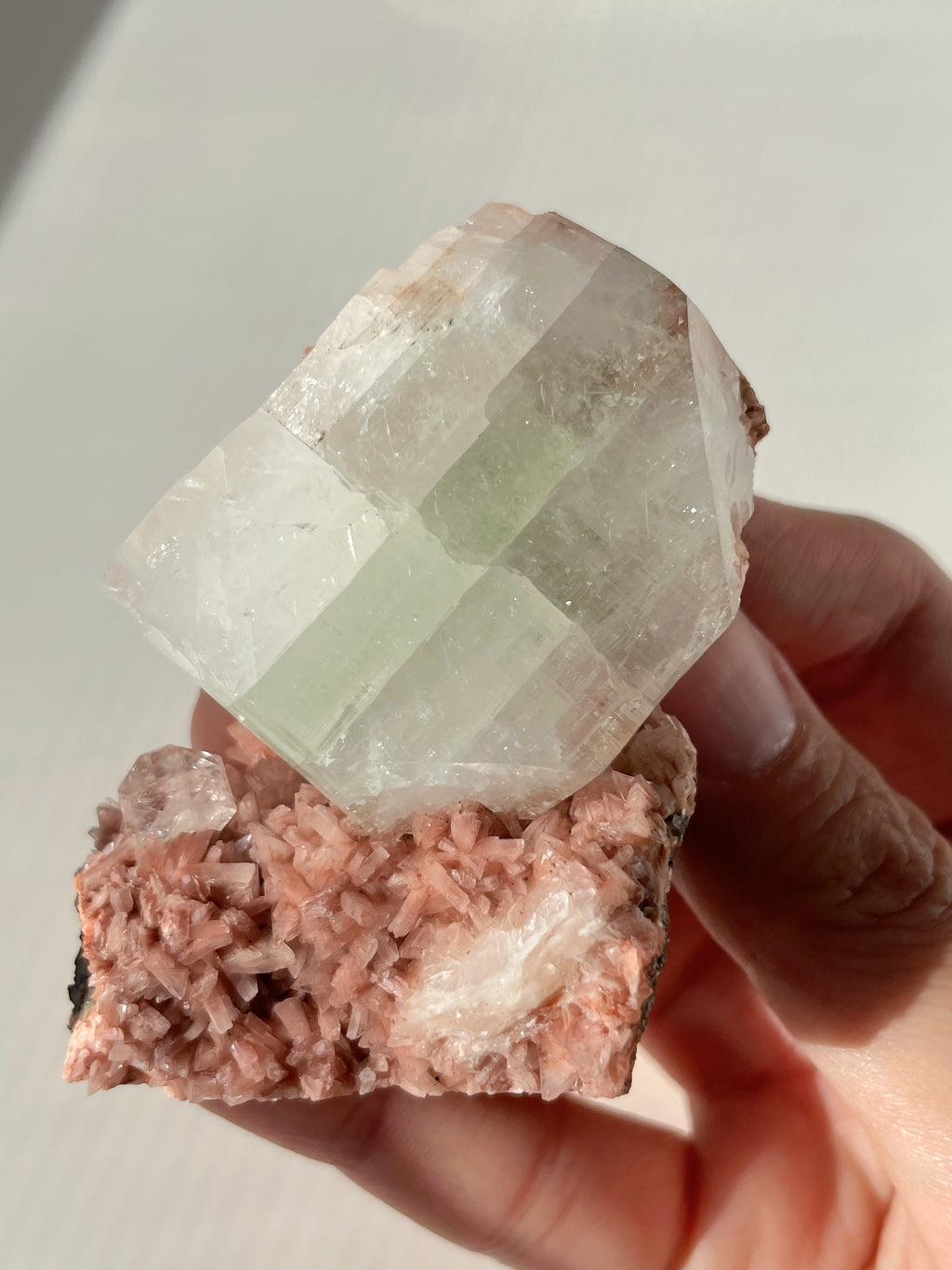 Beautiful pink Heulandite and Apophyllite crystal specimen held in hand, showcasing its unique formations and colors.