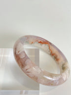 Beautiful flower agate bangle showcasing soft pink and white patterns, displayed on a clear stand.