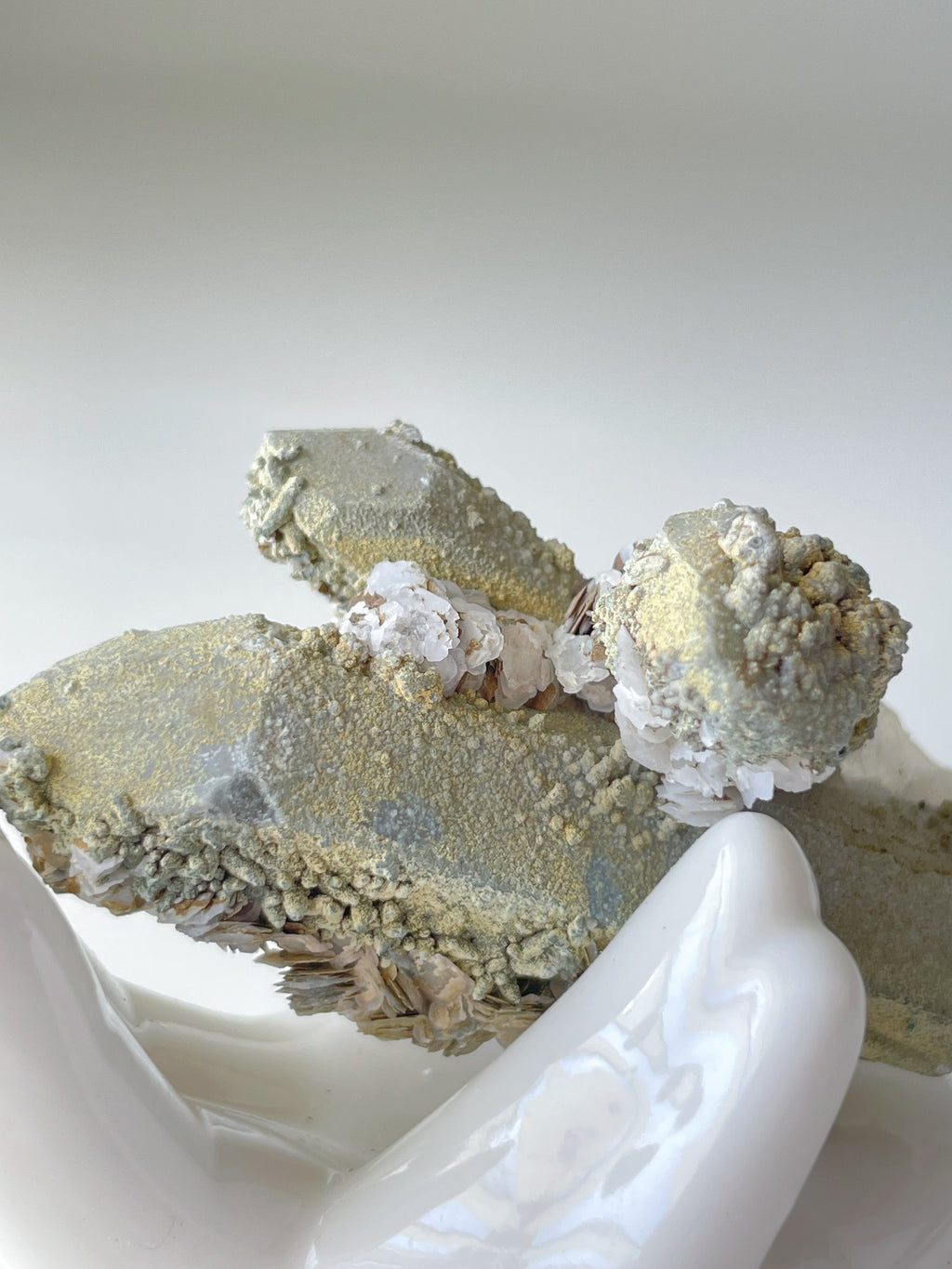 Beautiful Rosette Petal Calcite on Quartz specimen, showcasing intricate textures and colors, held gently in a hand.